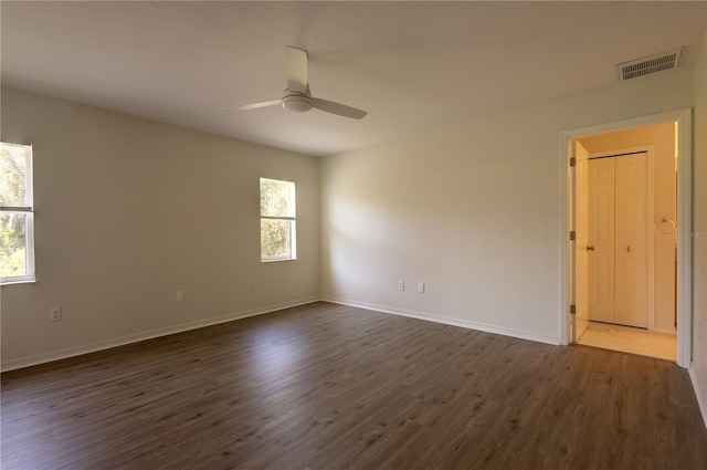 spare room with dark wood-type flooring, baseboards, visible vents, and ceiling fan