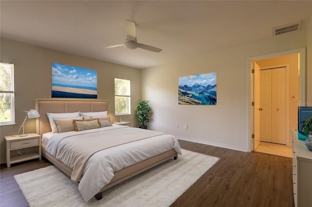 bedroom with ceiling fan, visible vents, baseboards, and wood finished floors