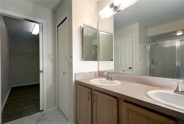 bathroom with a shower stall, double vanity, marble finish floor, and a sink