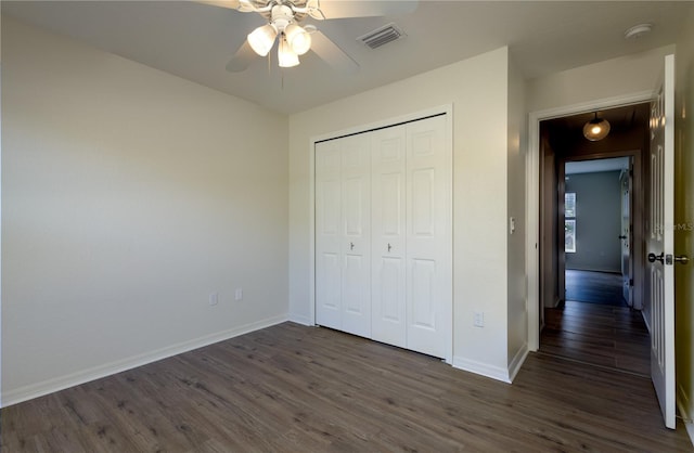 unfurnished bedroom featuring visible vents, dark wood-style floors, baseboards, and a closet