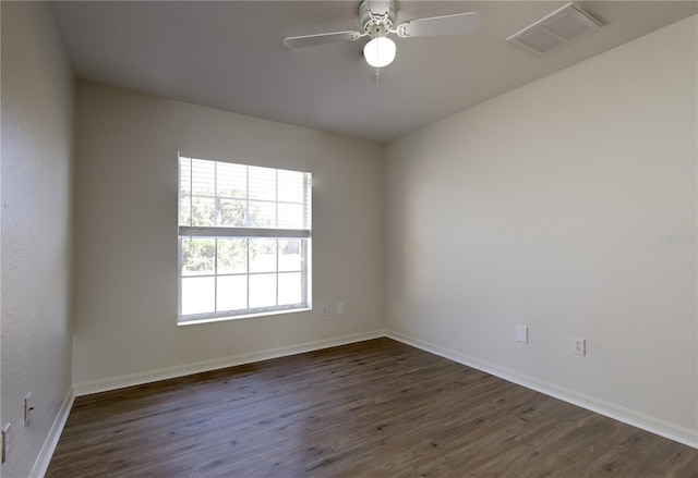 spare room with dark wood finished floors, a ceiling fan, visible vents, and baseboards