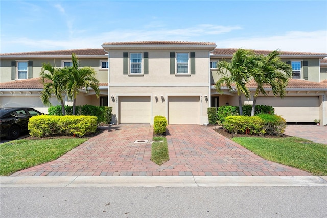 view of front of house featuring a tiled roof, an attached garage, driveway, and stucco siding