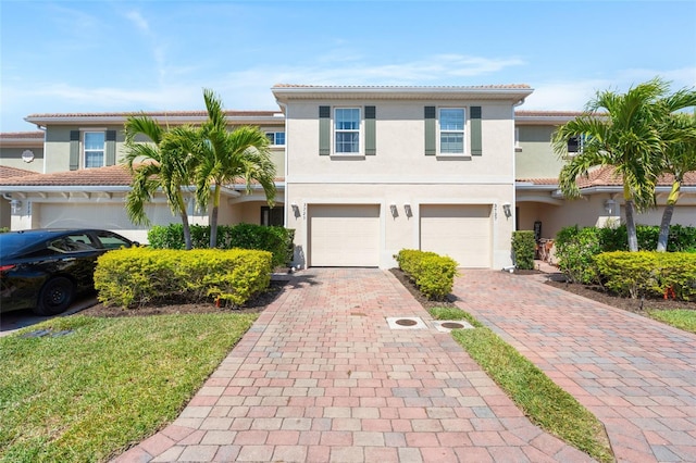 view of front of home featuring stucco siding, an attached garage, and decorative driveway