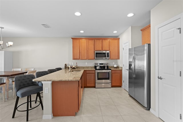 kitchen featuring visible vents, a sink, stainless steel appliances, a peninsula, and light stone countertops