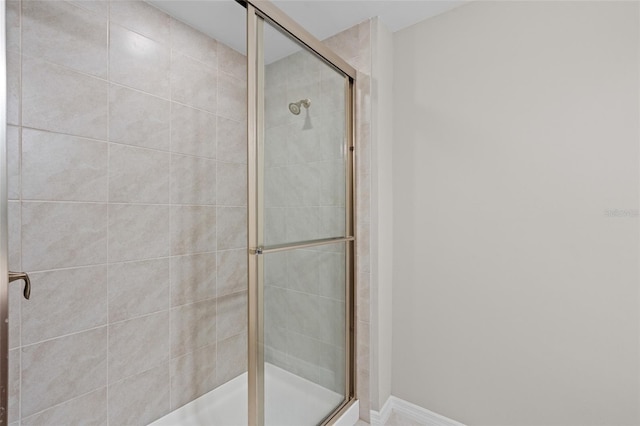 bathroom featuring a shower stall and baseboards