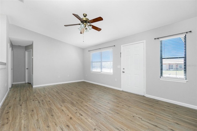 interior space with wood finished floors, a ceiling fan, baseboards, and vaulted ceiling