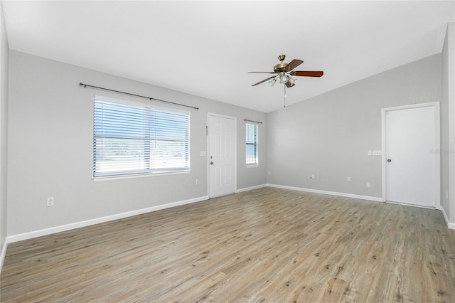 spare room featuring vaulted ceiling, light wood-style flooring, baseboards, and ceiling fan