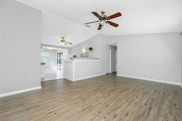 unfurnished living room featuring baseboards, light wood-style floors, a ceiling fan, and vaulted ceiling