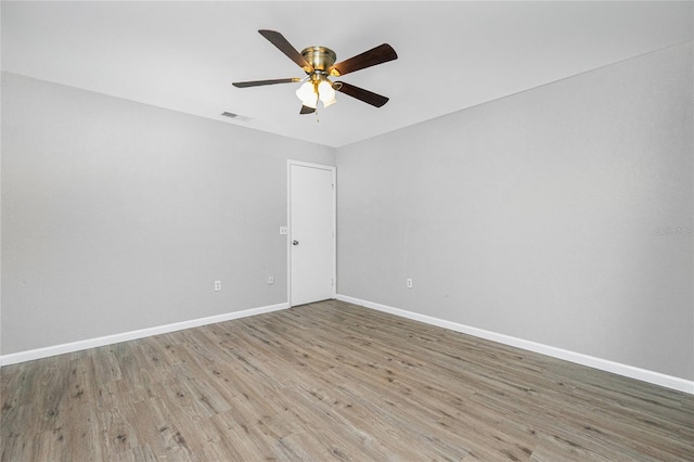 empty room with visible vents, a ceiling fan, baseboards, and wood finished floors