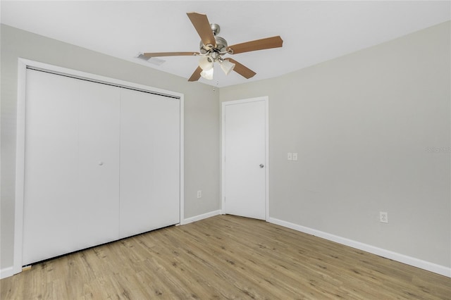 unfurnished bedroom featuring visible vents, wood finished floors, a closet, baseboards, and ceiling fan