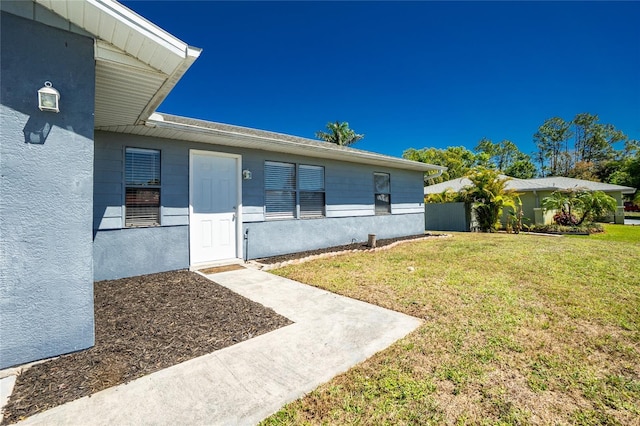 doorway to property with a lawn and stucco siding