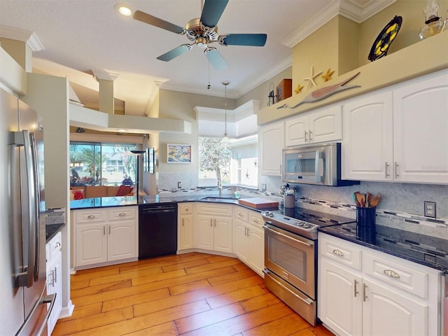 kitchen with a sink, ornamental molding, stainless steel appliances, white cabinetry, and tasteful backsplash