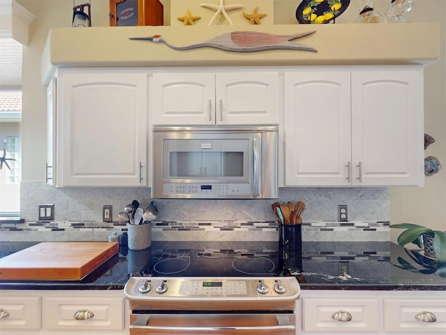 kitchen featuring dark stone countertops, decorative backsplash, appliances with stainless steel finishes, and white cabinets