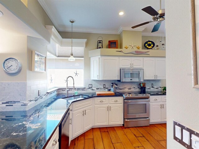 kitchen featuring ornamental molding, a sink, appliances with stainless steel finishes, white cabinets, and light wood finished floors