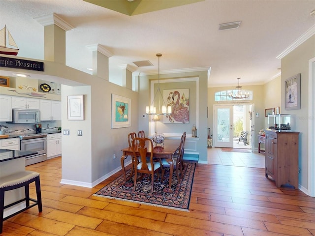 dining area with a notable chandelier, crown molding, light wood-type flooring, and visible vents