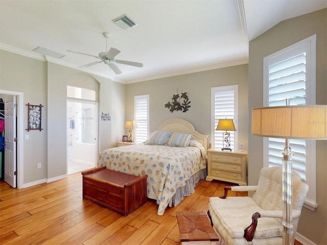 bedroom featuring visible vents, a walk in closet, light wood-style floors, and ornamental molding