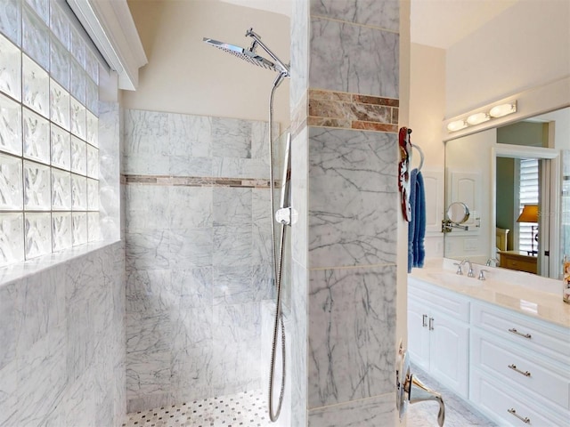 full bath featuring a marble finish shower and vanity