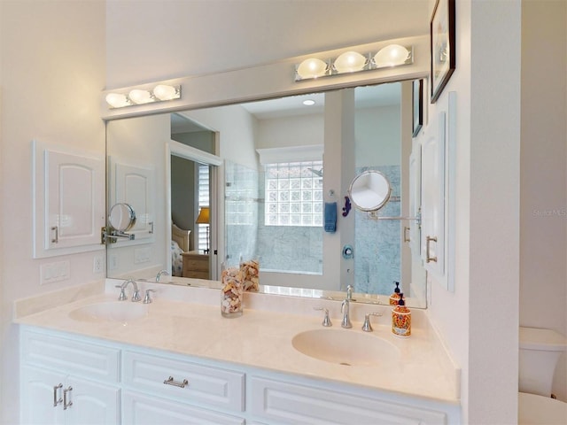 ensuite bathroom featuring double vanity, connected bathroom, toilet, and a sink