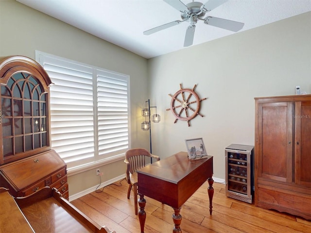 office area with wine cooler, baseboards, and light wood-type flooring