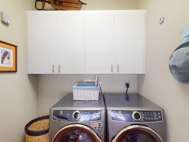 laundry room featuring washing machine and clothes dryer and cabinet space