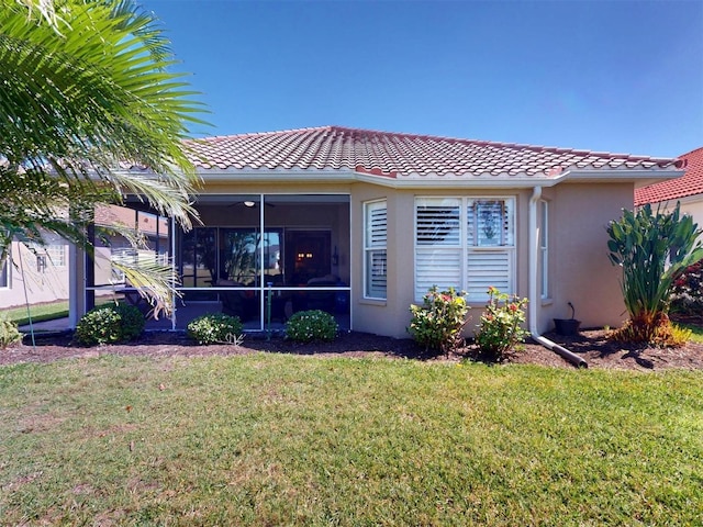 exterior space with stucco siding, a tiled roof, a front yard, and a sunroom