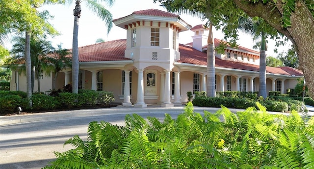 mediterranean / spanish house featuring stucco siding and a tiled roof