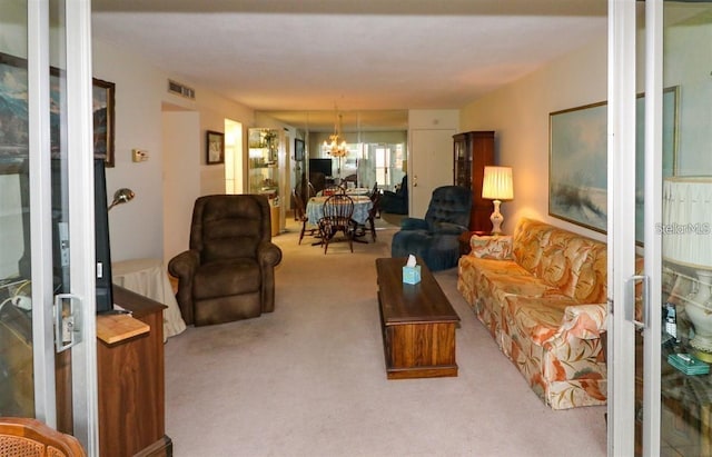 living room with visible vents, carpet floors, and an inviting chandelier