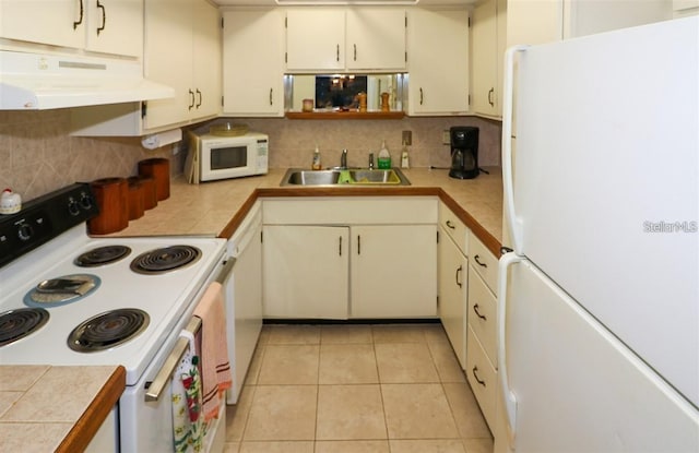 kitchen with backsplash, under cabinet range hood, light tile patterned floors, white appliances, and a sink