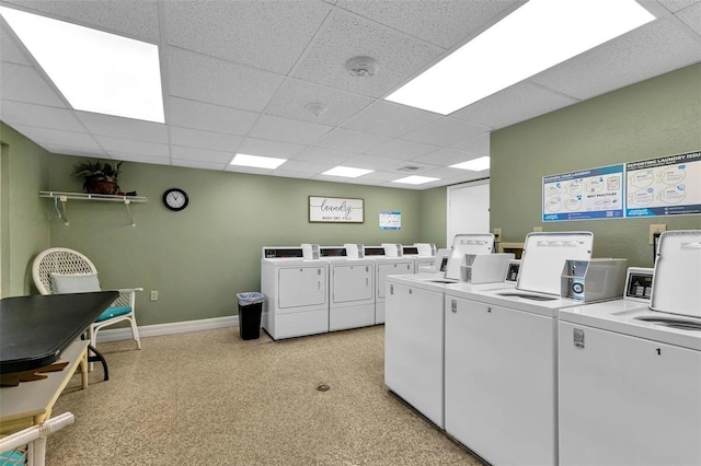 common laundry area featuring washing machine and clothes dryer, light floors, and baseboards