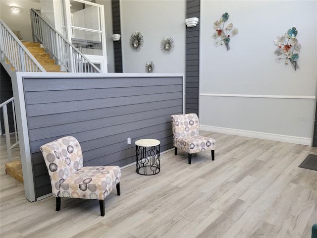 sitting room with baseboards, wood finished floors, and stairs