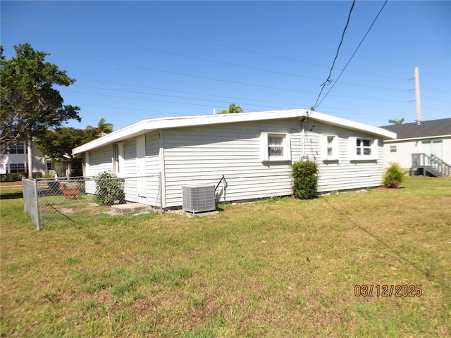 view of property exterior with a lawn, central AC, and fence