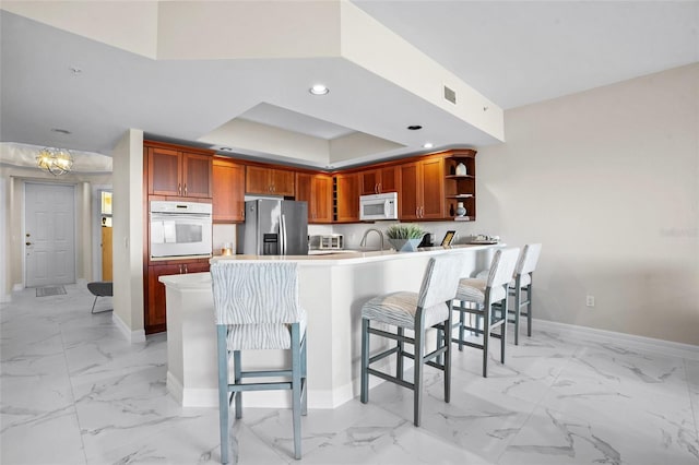 kitchen featuring visible vents, marble finish floor, white appliances, and a peninsula