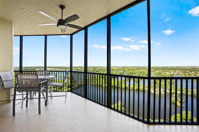 unfurnished sunroom with a water view and ceiling fan