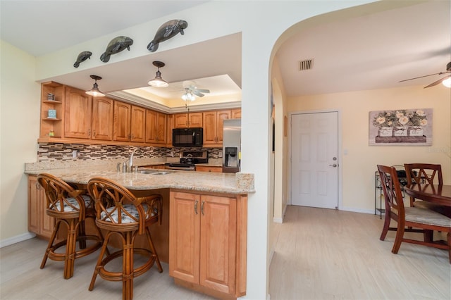 kitchen featuring visible vents, backsplash, ceiling fan, a tray ceiling, and appliances with stainless steel finishes