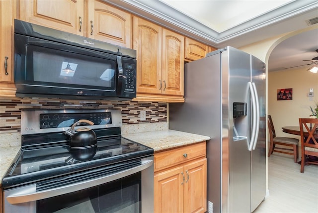 kitchen featuring backsplash, ceiling fan, light stone countertops, arched walkways, and stainless steel appliances