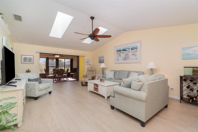 living room with visible vents, light wood-style flooring, vaulted ceiling with skylight, baseboards, and ceiling fan