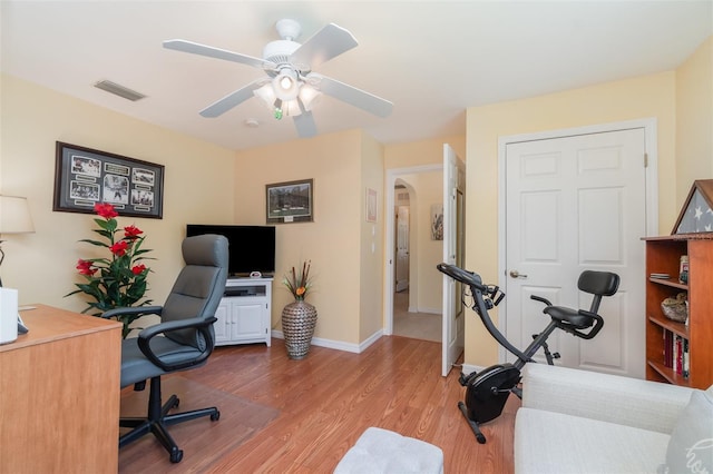 home office featuring visible vents, wood finished floors, arched walkways, baseboards, and ceiling fan