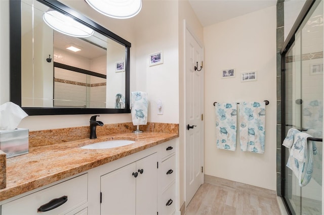 bathroom with vanity, wood finished floors, and a shower stall