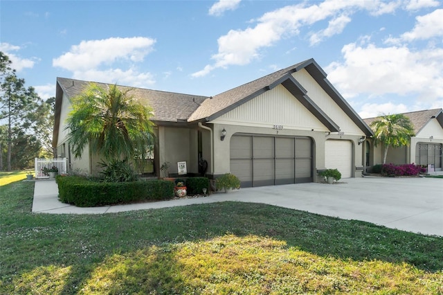 view of front facade with concrete driveway, an attached garage, a front yard, and a shingled roof