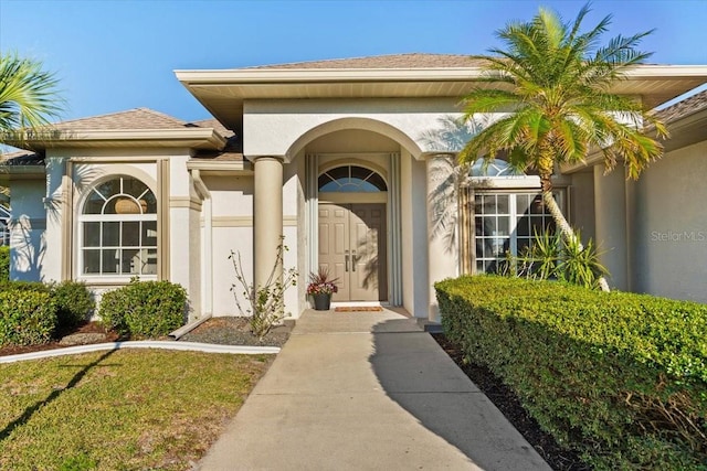property entrance with stucco siding and a shingled roof