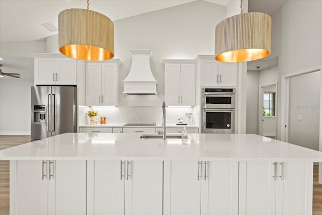 kitchen with a spacious island, premium range hood, appliances with stainless steel finishes, white cabinetry, and a sink