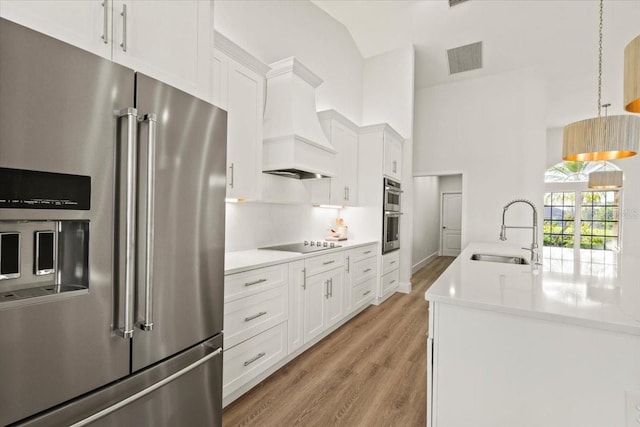 kitchen featuring visible vents, custom range hood, a sink, appliances with stainless steel finishes, and white cabinets