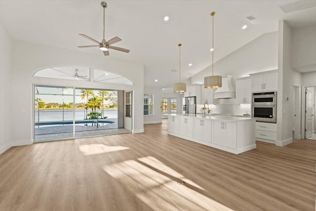 kitchen featuring a ceiling fan, custom range hood, a sink, open floor plan, and stainless steel appliances