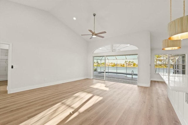unfurnished living room featuring baseboards, high vaulted ceiling, light wood-style flooring, and a ceiling fan