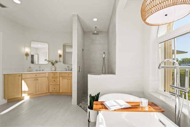 bathroom with a sink, a freestanding bath, walk in shower, and double vanity