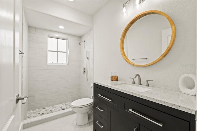 bathroom featuring vanity, toilet, and a tile shower