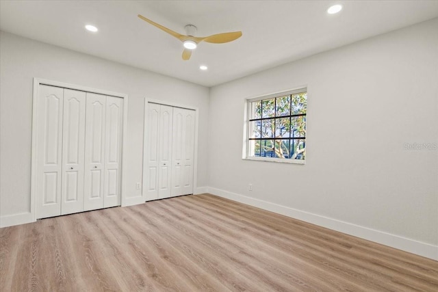 unfurnished bedroom with recessed lighting, baseboards, multiple closets, and wood finished floors