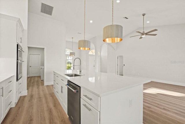kitchen featuring visible vents, a center island with sink, a sink, stainless steel appliances, and light wood-style floors