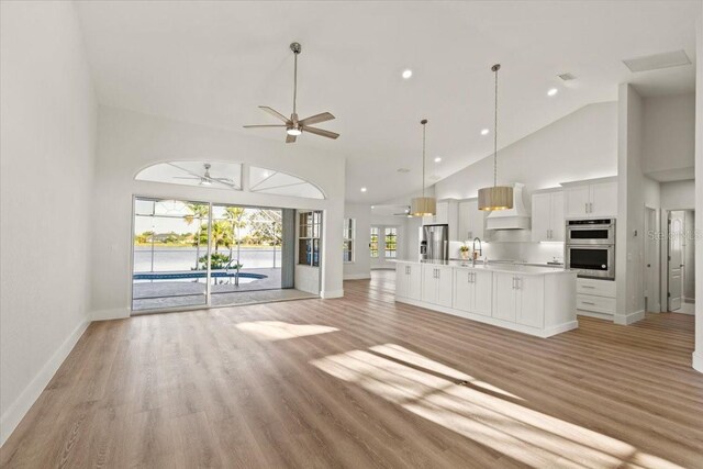 12800 SW Pembroke Cir N, Lake Suzy, FL 34269 - unfurnished living room featuring high vaulted ceiling, ceiling fan, baseboards, a sink, and light wood finished floors
