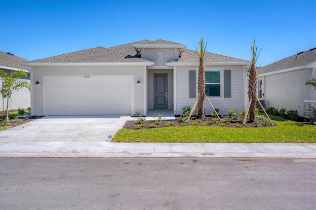 view of front of house featuring concrete driveway, a garage, and a front yard